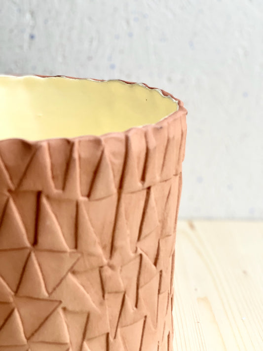 Kavlad kruka med stämplad yta. Glaserad ljusgul insida. Rå utsida