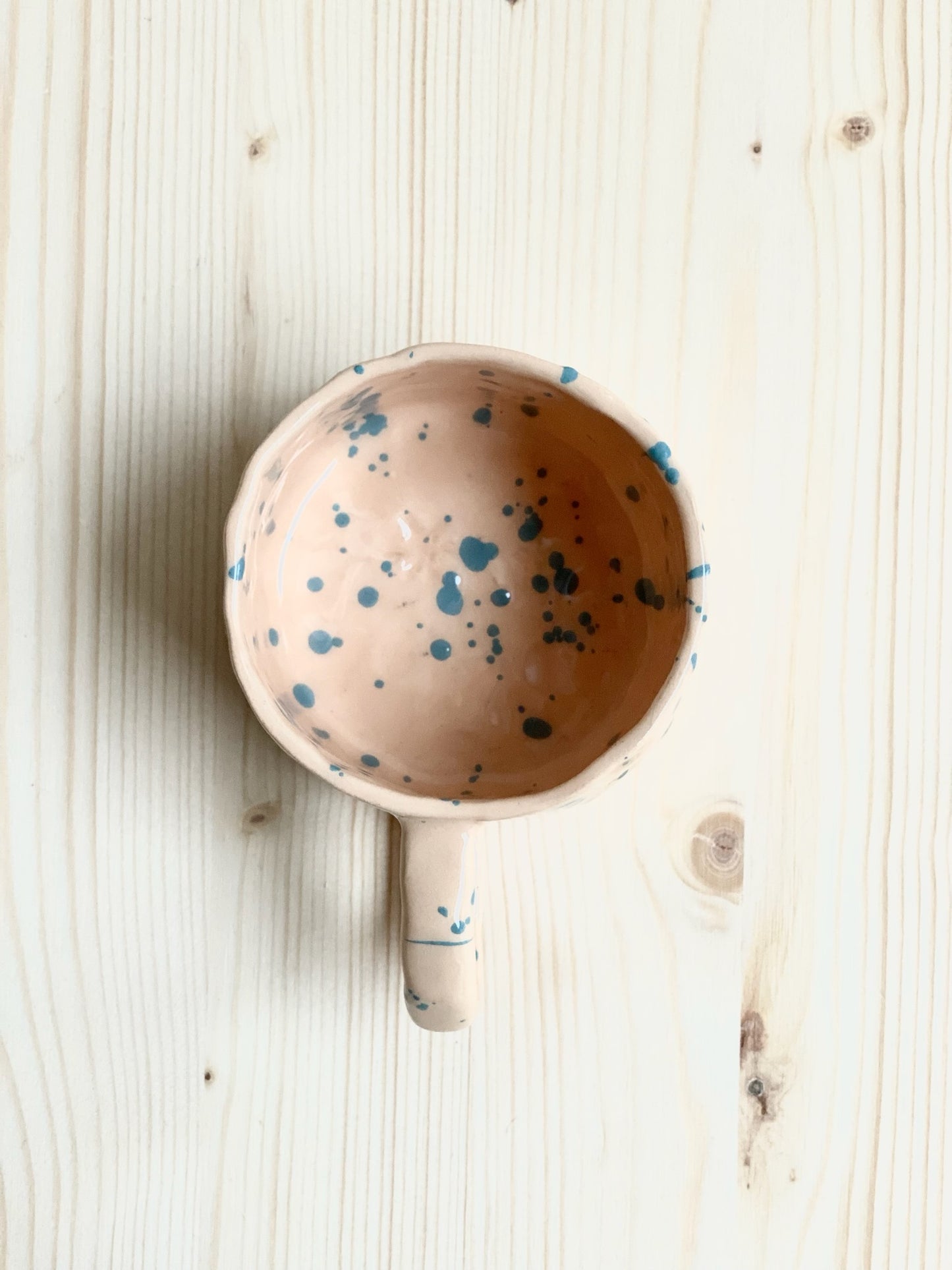 Tummad kopp. Ljust orange med mörka turkosa stänk