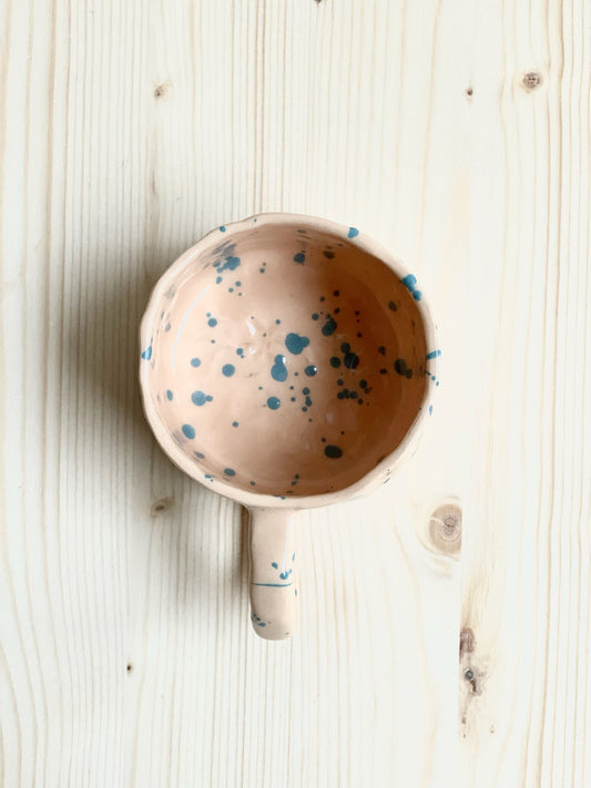 Tummad kopp. Ljust orange med mörka turkosa stänk