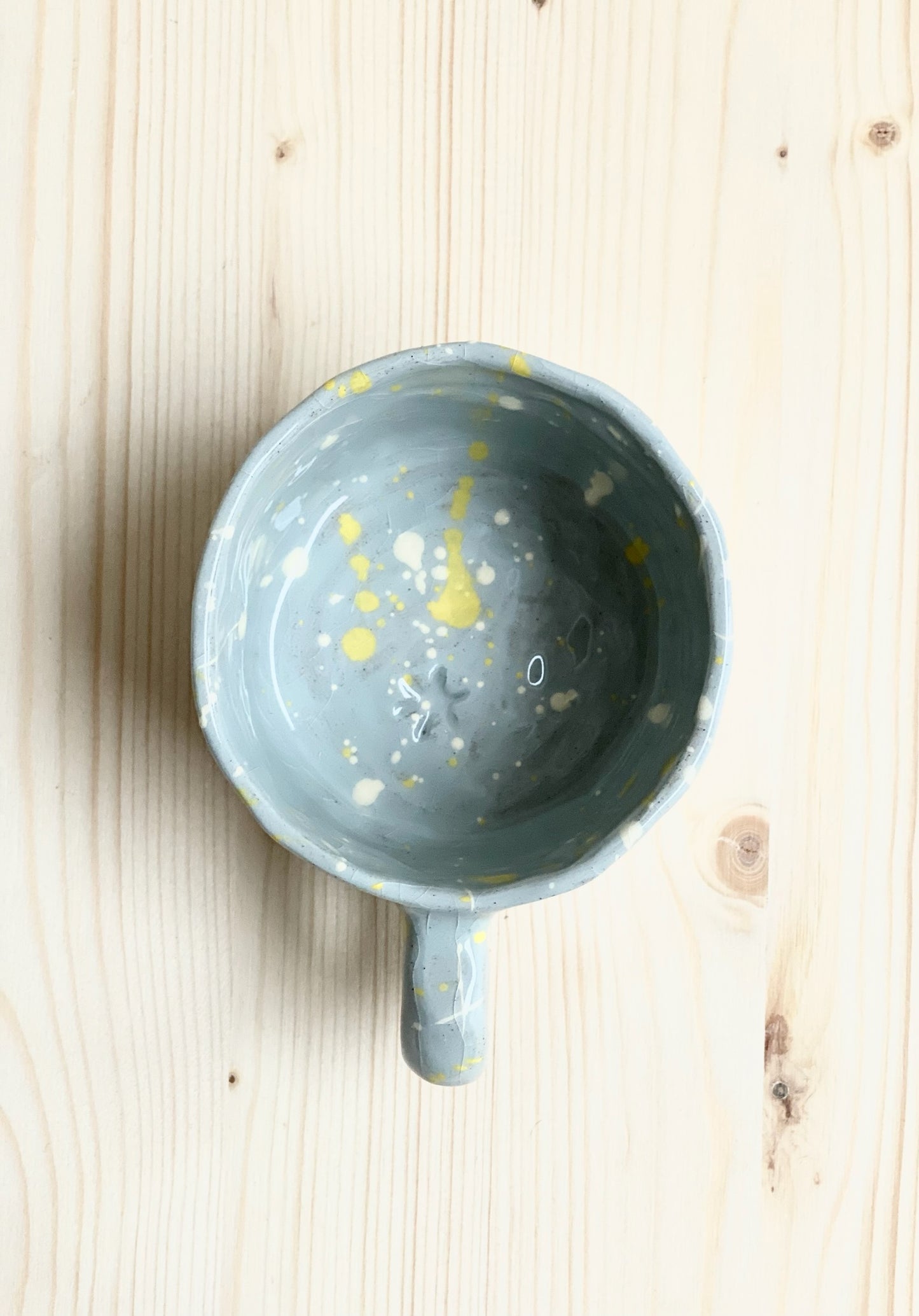 Tummad kopp. Ljusblå med vita och gula stänk